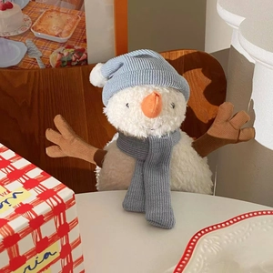 Cute snowman plush doll with blue knit hat and scarf sitting on a white table