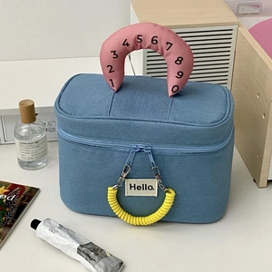 Macro detail of navy blue canvas makeup bag with pink numeric handle and yellow spiral decor