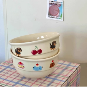 Detail of cream ceramic bowls with hand-painted dachshund and cupcake illustrations