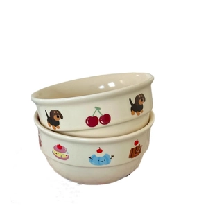 Two stacked cream ceramic bowls with cute cartoon dachshund and cherry patterns