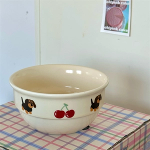 Detail view of cream ceramic bowl featuring cute hand-drawn dachshund and cherry patterns