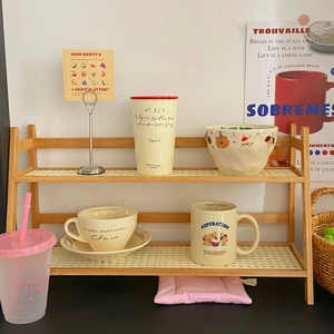 Detail of a two-tier wooden desk organizer featuring cream non-slip mats and side handles