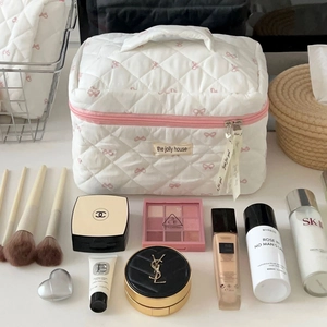 Quilted white cosmetic bag with pink bow pattern and top handle for travel storage