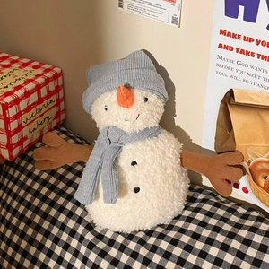 Close-up of plush snowman doll with blue knitted hat and scarf in cozy holiday setting