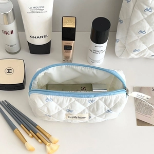 Détail de la trousse de maquillage matelassée avec nœuds bleus et intérieur spacieux