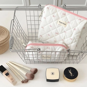 Close-up of quilted cosmetic bags with pink bow print in a silver basket display