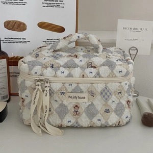 Detail of quilted bear cosmetic bag featuring a sturdy handle and ribbon zipper pullers