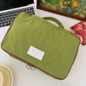 Detailed view of a green grid nylon organizer bag on a desk with a brown zipper