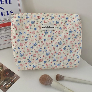 Detailed macro view of floral corduroy makeup bag with quilted texture and brand label