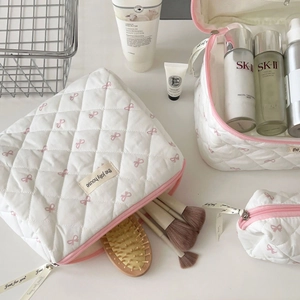 Quilted white cosmetic bags with pink bow print and ribbon detail for travel storage