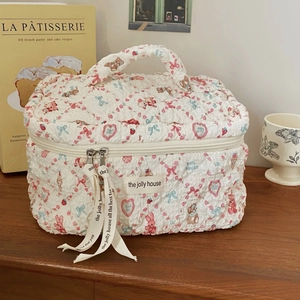 Quilted floral bear makeup bag with top handle and blue bows on a wooden surface