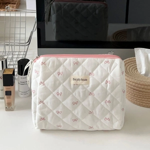 Detailed shot of white quilted cotton cosmetic bag with pink bow pattern and ribbon