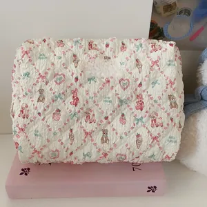 Close-up of quilted cotton makeup bag with teddy bear patterns and fabric logo label