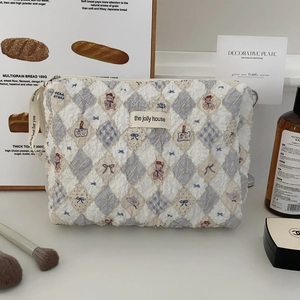 Macro shot of quilted bear pattern cosmetic bag with ribbon zipper puller details