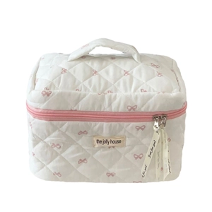 White quilted makeup bag with pink bow prints and a sturdy top handle for travel