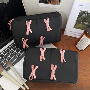 Macro detail of black nylon makeup bag featuring pink 3D ribbon bows and zipper