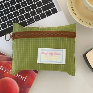 Green checkered mini travel pouch for earphones and coins on an office desk setting