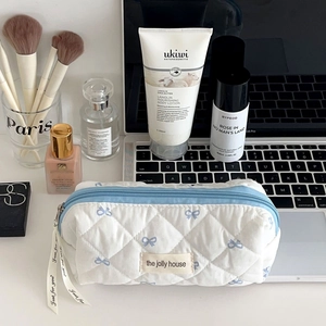Détail de la trousse de maquillage matelassée avec nœuds bleus et ruban décoratif