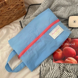 Light blue checkered waterproof nylon travel pouch with vibrant pink zipper closure