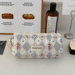 Detail of quilted bear makeup bag featuring blue diamond patterns and a woven label