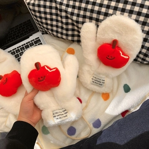 Detail of white plush gloves with red apple patch and lanyard on cozy fabric background