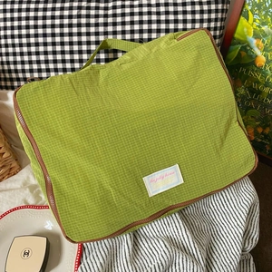 Detail of green plaid nylon travel storage bag with handle and secure zipper closure
