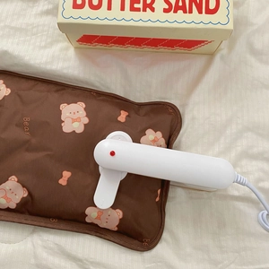 Close-up of a brown electric hot water bottle with cute bear print and white charging clip