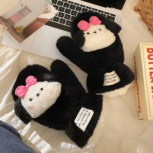 Close-up of cute black plush puppy mittens with a pink bow in a cozy winter setting