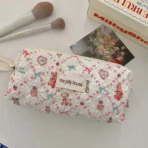 Close-up of quilted cosmetic bag with cute cartoon rabbit prints and woven brand label