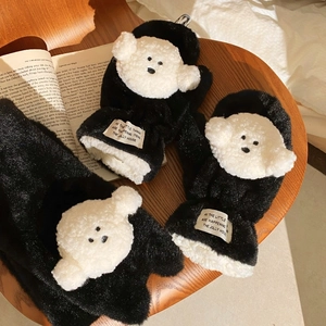 Detail von plüschigen schwarzen Winterhandschuhen mit weißem Teddybär-Patch und Webetikett
