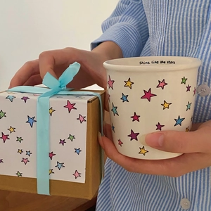 Close-up of ceramic star mug with Shine Like the stars text and gift box packaging