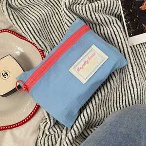 Detail of light blue checkered travel pouch with pink zipper and round metal puller