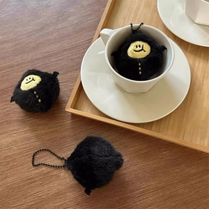 Three cute black demon lemon plush keychains displayed on a coffee cup and tray