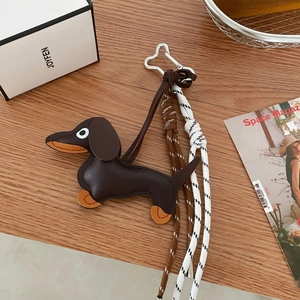 Brown leather dachshund dog keychain with bone metal clip and woven rope on wooden table