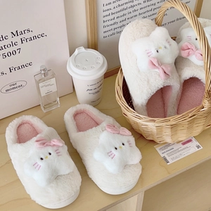 Plush cat slippers with pink bow and warm fleece lining on a minimalist background