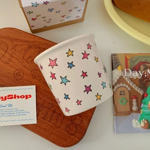 Colorful star pattern ceramic mug with matching gift box on a cozy wooden tray