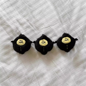 Three cute black and yellow devil lemon plush keychains on white fabric background