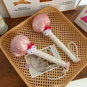 Close-up of pink satin massage hammers with Hello Kitty plush heads in a rustic basket