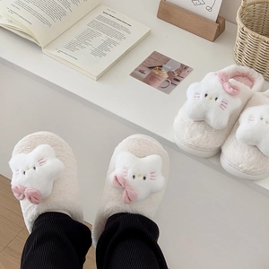 Detailed view of plush cat slippers with star patches and pink bow decoration