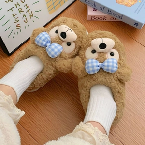 Nahaufnahme brauner Plüsch-Hausschuhe mit hellblauer Karoschleife und weicher Teddy-Textur