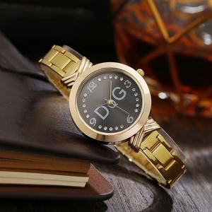 Detail of gold crystal-encrusted watch featuring black dial with D&G logo and metal strap