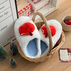 Gros plan de chaussons en peluche blanche avec poupée cœur rouge et doublure en polaire