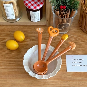Close-up of four orange creative ceramic dessert spoons with cartoon food handle shapes