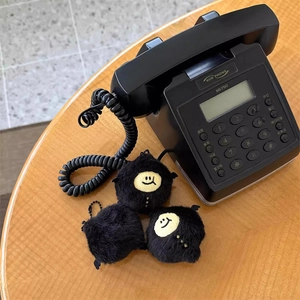 Close-up of three black plush demon lemon keychains with smiley faces on a wooden table