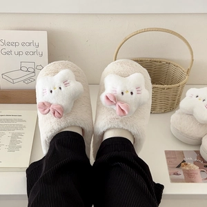 Detailed view of plush cat slippers with pink bow in a cozy home setting with decor