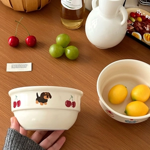Süße cremefarbene Keramikschüssel mit Dackel- und Kirschmotiven auf dem Holztisch