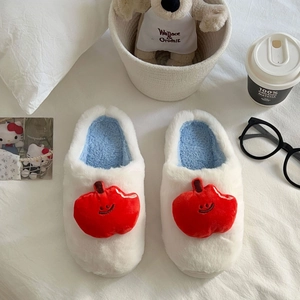 Gros plan sur les chaussons d'hiver en peluche avec un motif pomme brodé souriant