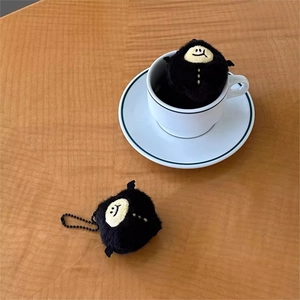 Close-up of a cute black devil lemon plush charm inside a white ceramic coffee cup