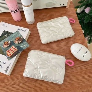 Detail view of white quilted heart and bow mini pouches with pink zipper pulls