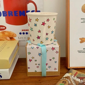 Ceramic star pattern mug with matching gift box on a cozy wooden tabletop setting
